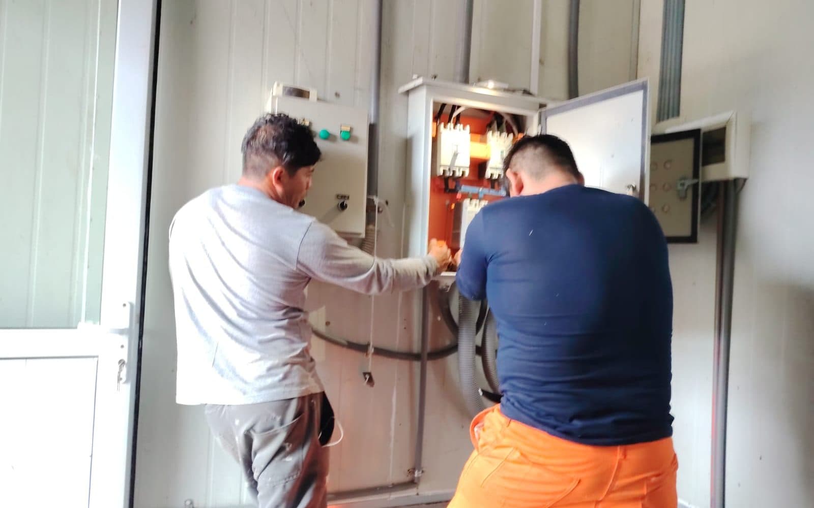 Dos técnicos trabajando sobre un tablero eléctrico abierto